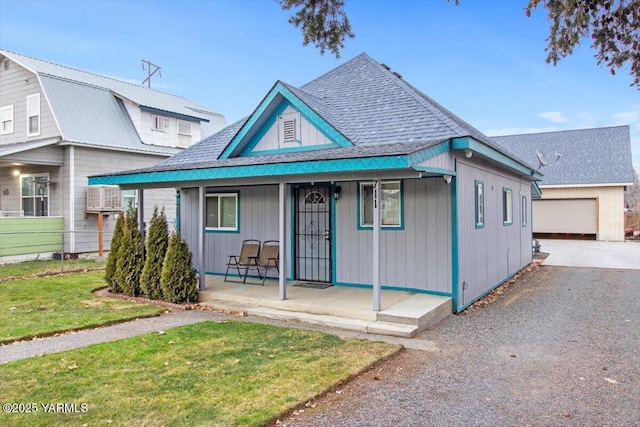 view of front of home featuring covered porch, a shingled roof, and a front lawn