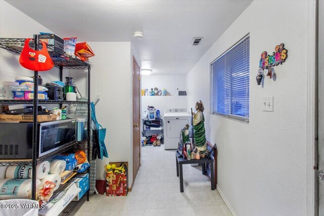 hallway featuring visible vents, light floors, and washer / dryer