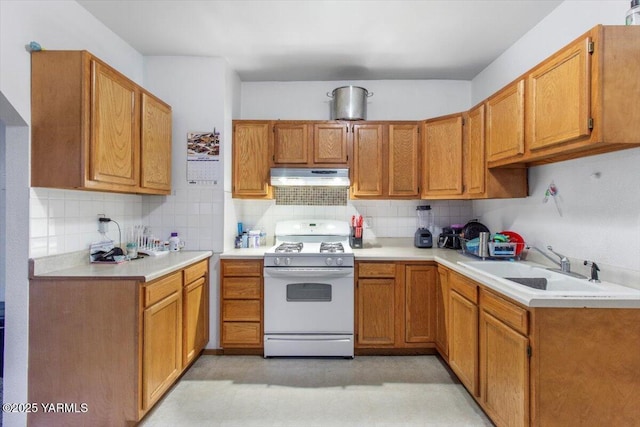 kitchen featuring brown cabinets, under cabinet range hood, white gas range oven, and light countertops