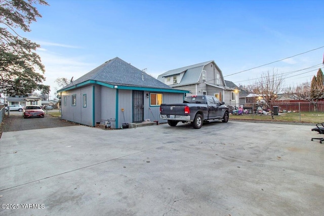 view of side of property featuring driveway, fence, and a gambrel roof