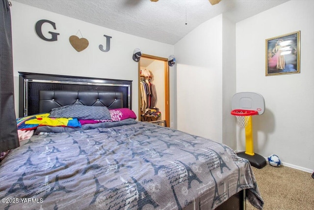 carpeted bedroom with a walk in closet, ceiling fan, a textured ceiling, and baseboards