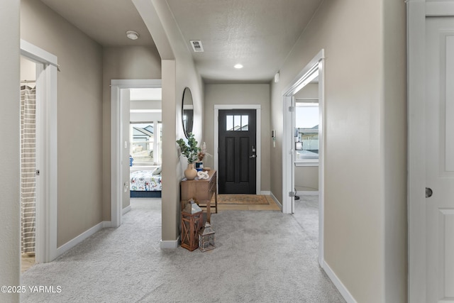 foyer entrance with carpet floors, baseboards, visible vents, and a textured ceiling