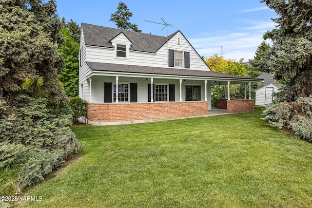 view of front facade featuring a porch, brick siding, a storage unit, a shingled roof, and a front lawn