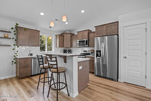 19700 N Beers Rd, Prosser, WA 99350 - kitchen with appliances with stainless steel finishes, a breakfast bar, tasteful backsplash, light wood finished floors, and lofted ceiling