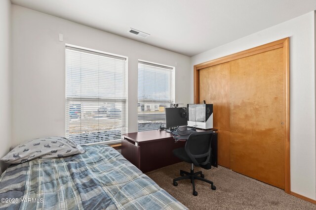 carpeted bedroom featuring visible vents and a closet