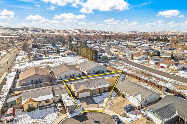 snowy aerial view featuring a residential view and a mountain view