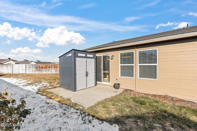 rear view of property with an outbuilding, fence, a storage shed, and a patio