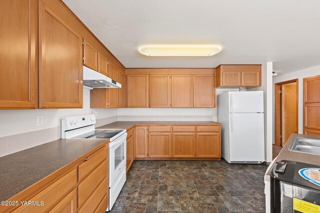 kitchen featuring stone finish flooring, white appliances, dark countertops, and under cabinet range hood