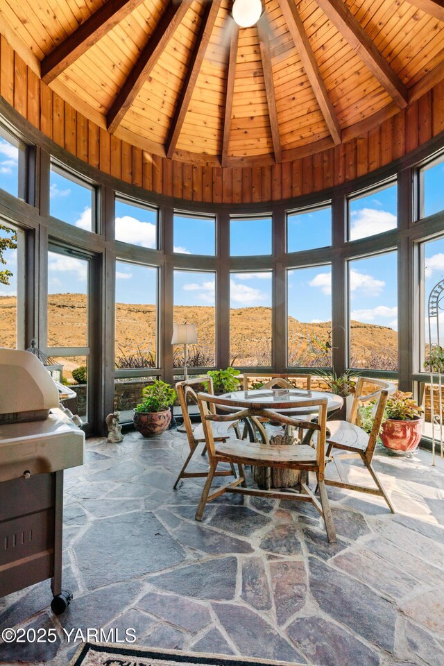 sunroom / solarium featuring vaulted ceiling with beams, wooden ceiling, and a mountain view