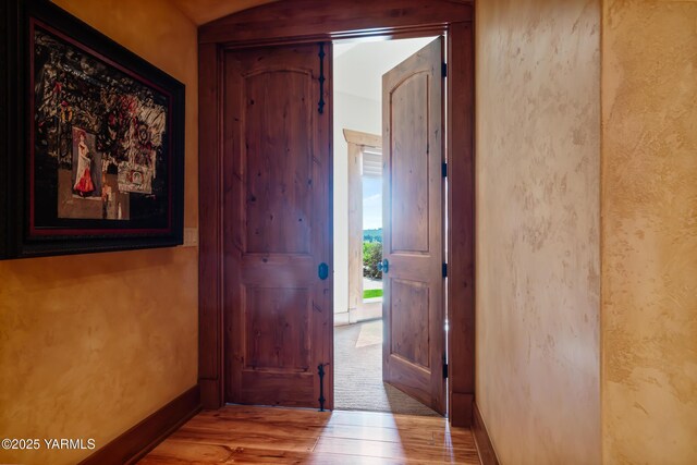 hall featuring light wood-style flooring and baseboards