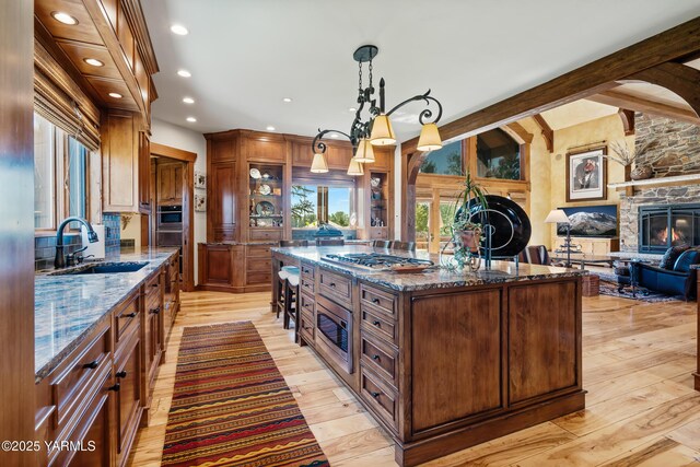 kitchen featuring stainless steel appliances, a center island, decorative light fixtures, and dark stone countertops