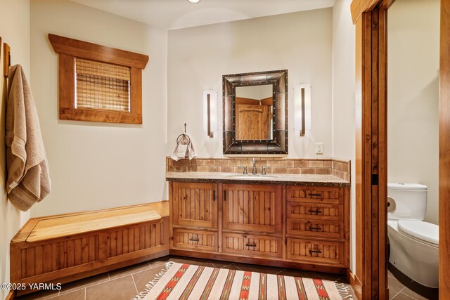 bathroom with toilet, vanity, decorative backsplash, and tile patterned floors