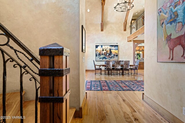 corridor featuring stairway, a notable chandelier, a towering ceiling, and wood finished floors