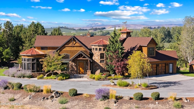 view of front facade featuring a garage, stone siding, a mountain view, and concrete driveway