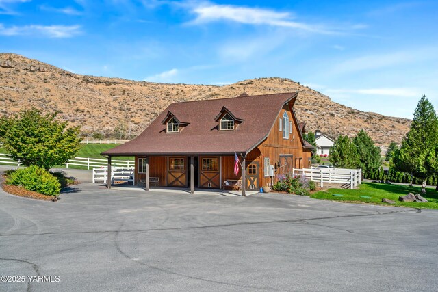 view of front facade with an outbuilding, roof with shingles, an exterior structure, and a mountain view