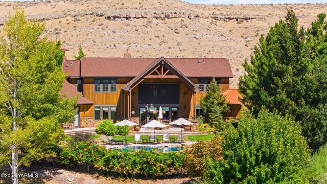 rear view of house featuring a fenced in pool, a mountain view, and a chimney