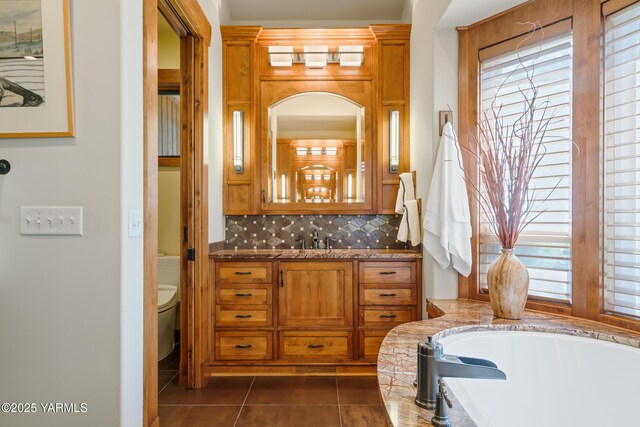 bathroom with vanity, backsplash, tile patterned flooring, and toilet