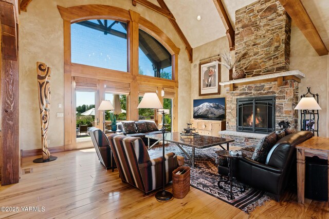 living room with light wood finished floors, a fireplace, high vaulted ceiling, and beamed ceiling