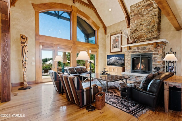 living room with light wood finished floors, a fireplace, high vaulted ceiling, and beamed ceiling