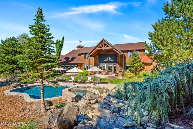 outdoor pool with an in ground hot tub, a patio area, and fence