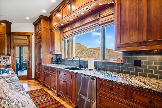 kitchen featuring light stone counters, appliances with stainless steel finishes, a mountain view, a sink, and light wood-type flooring