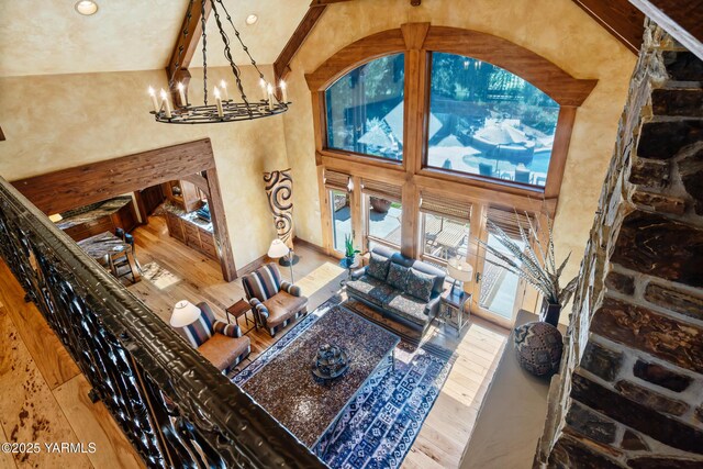 living area with a high ceiling, a chandelier, and wood finished floors