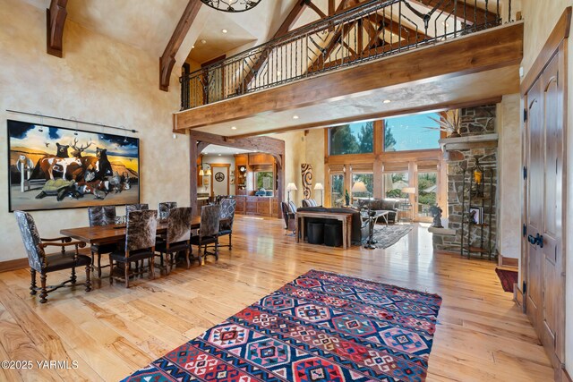 dining space with a high ceiling, baseboards, wood finished floors, and beamed ceiling