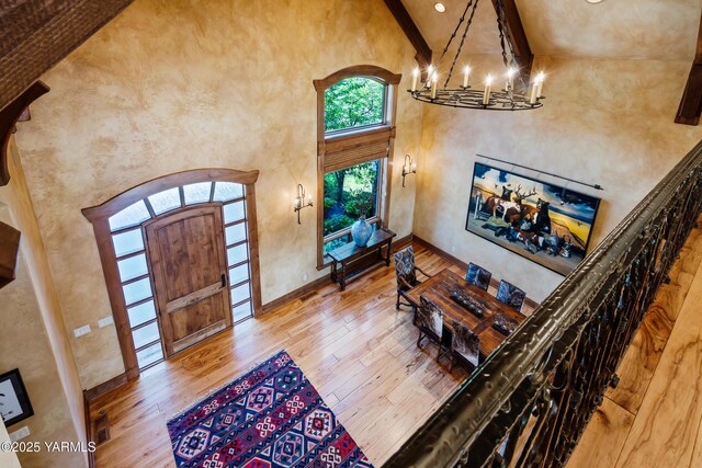 foyer with a chandelier, baseboards, a high ceiling, and wood finished floors