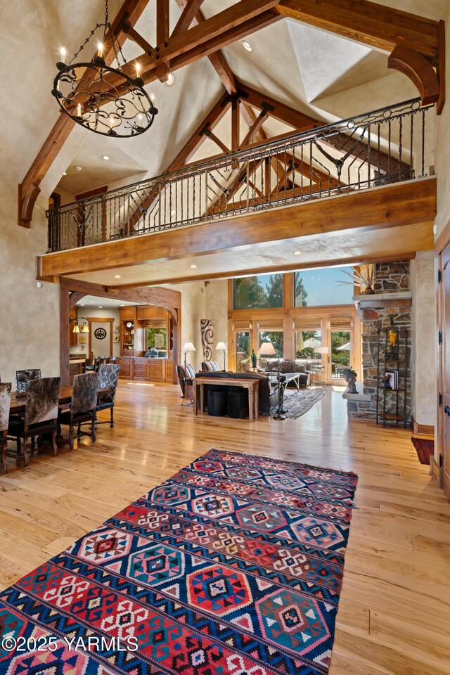 living area with a chandelier, high vaulted ceiling, wood finished floors, and beam ceiling