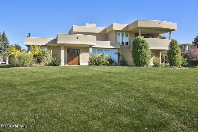 view of front of house featuring a front yard, a chimney, and stucco siding