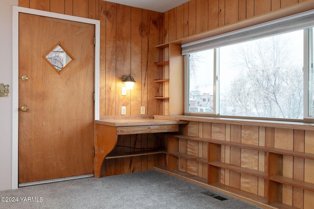 unfurnished office featuring wooden walls, visible vents, and carpet flooring