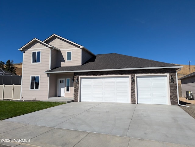 view of front of home with a garage, a shingled roof, fence, driveway, and stone siding