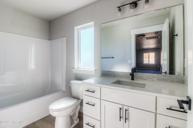 full bath featuring toilet, washtub / shower combination, wood finished floors, and vanity