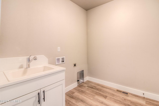 clothes washing area with hookup for a washing machine, visible vents, light wood-style flooring, hookup for an electric dryer, and a sink