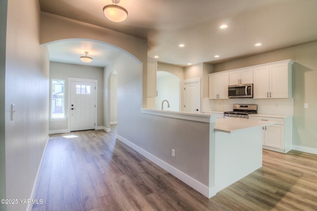 kitchen featuring light wood-type flooring, white cabinetry, appliances with stainless steel finishes, and light countertops