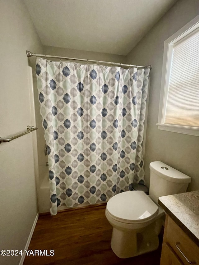 bathroom featuring toilet, wood finished floors, vanity, baseboards, and shower / bathtub combination with curtain