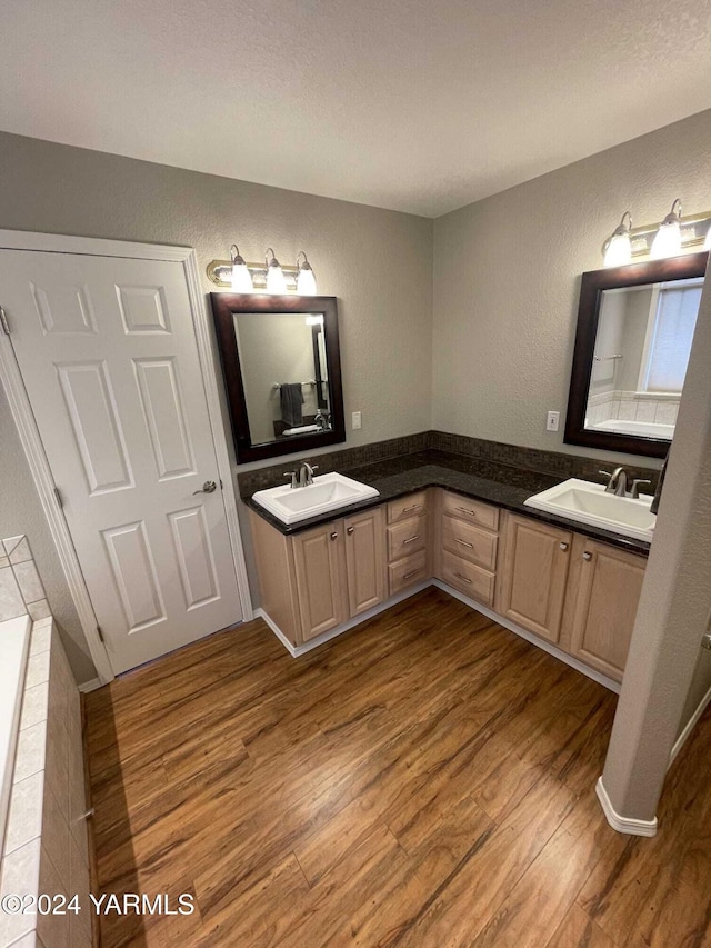 bathroom with double vanity, a sink, and wood finished floors