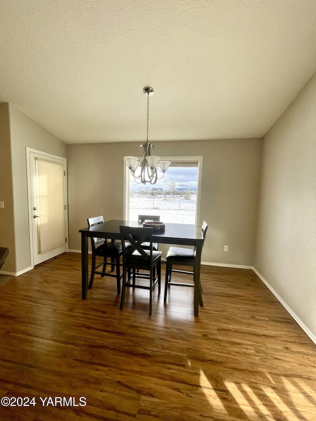 dining space featuring baseboards, a textured ceiling, wood finished floors, and an inviting chandelier