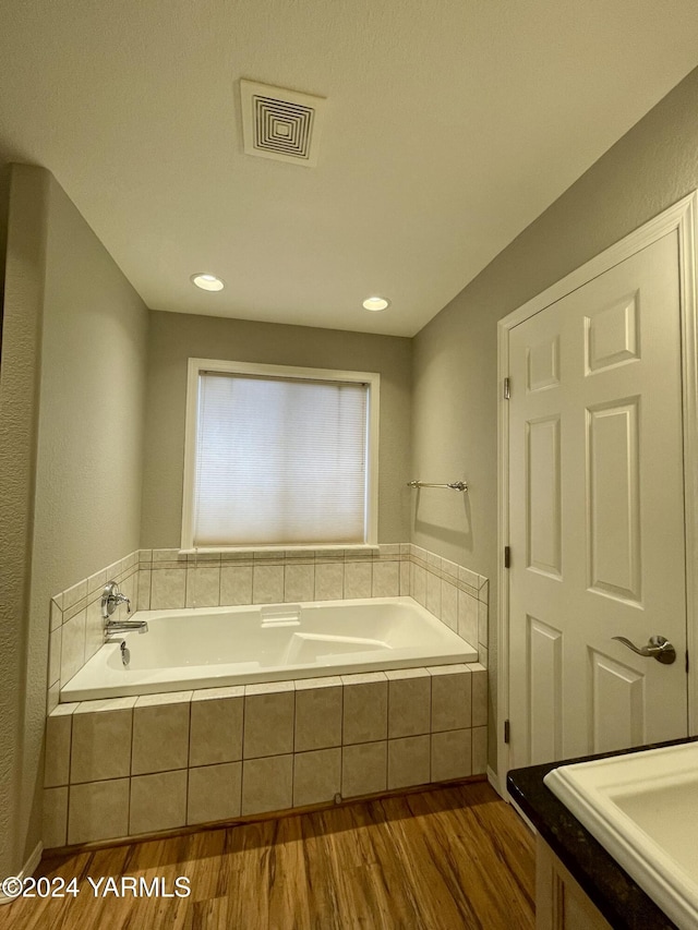 full bathroom with visible vents, a garden tub, and wood finished floors