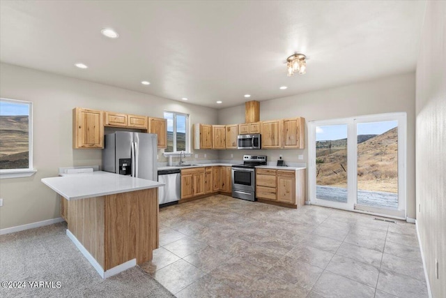 kitchen featuring stainless steel appliances, a peninsula, a sink, baseboards, and light countertops