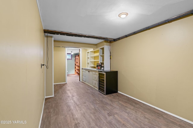 spare room featuring wine cooler, wood finished floors, and baseboards