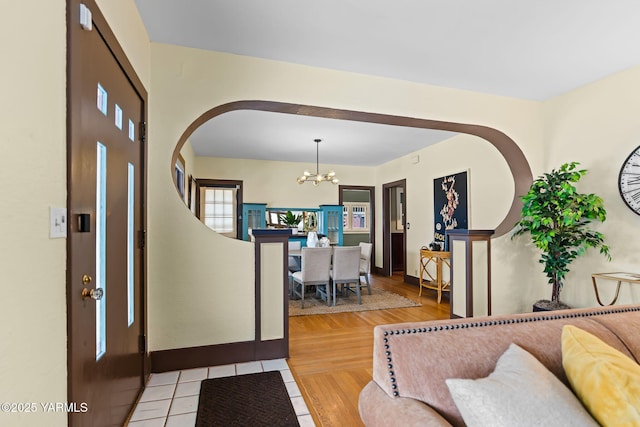 foyer entrance with stairs, light tile patterned floors, baseboards, and an inviting chandelier