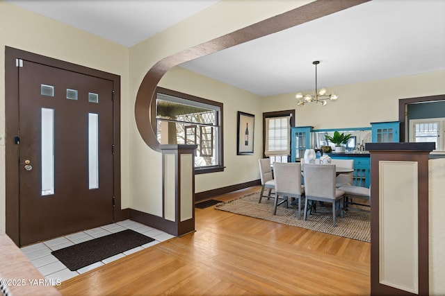 foyer featuring plenty of natural light, a notable chandelier, light wood finished floors, and baseboards