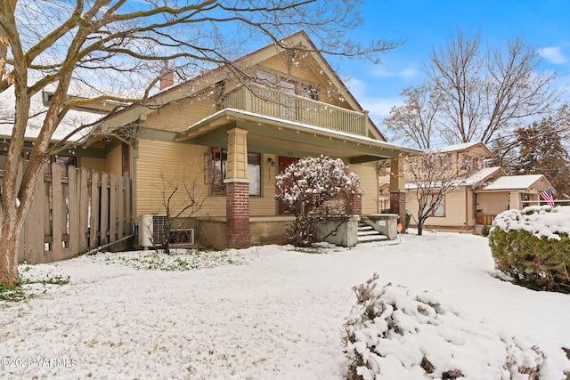 view of front of house featuring cooling unit, covered porch, fence, and a balcony