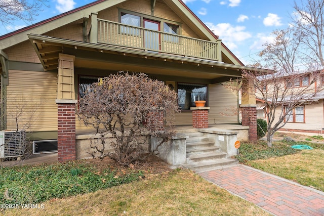 view of front facade featuring a balcony, cooling unit, and covered porch