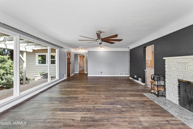 118 Glen Dr, Zillah, WA 98953 - unfurnished living room featuring ceiling fan, wood finished floors, a fireplace, and arched walkways
