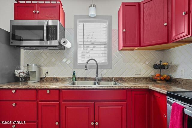 1319 S 15th Ave, Yakima, WA 98902 - kitchen featuring stainless steel microwave, red cabinetry, a sink, and decorative backsplash
