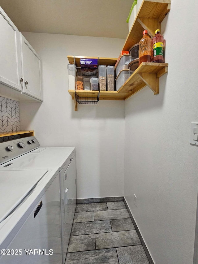 clothes washing area featuring baseboards, cabinet space, and washing machine and clothes dryer