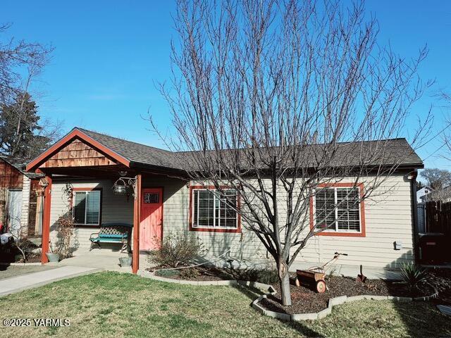 view of front of house with roof with shingles, fence, and a front yard