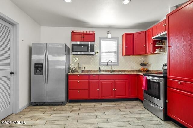 1319 S 15th Ave, Yakima, WA 98902 - kitchen featuring stainless steel appliances, red cabinetry, a sink, under cabinet range hood, and light wood-style flooring